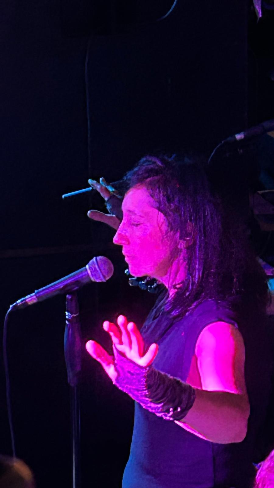 Alexandra am Mikrofon im violetten Bühnenlicht